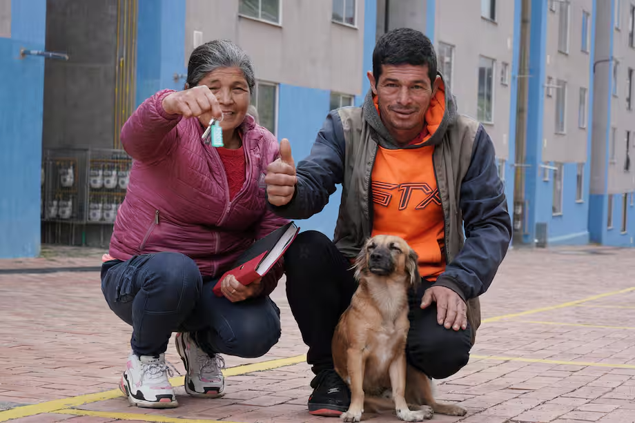 Fotografía familia con su mascota recibiendo vivienda